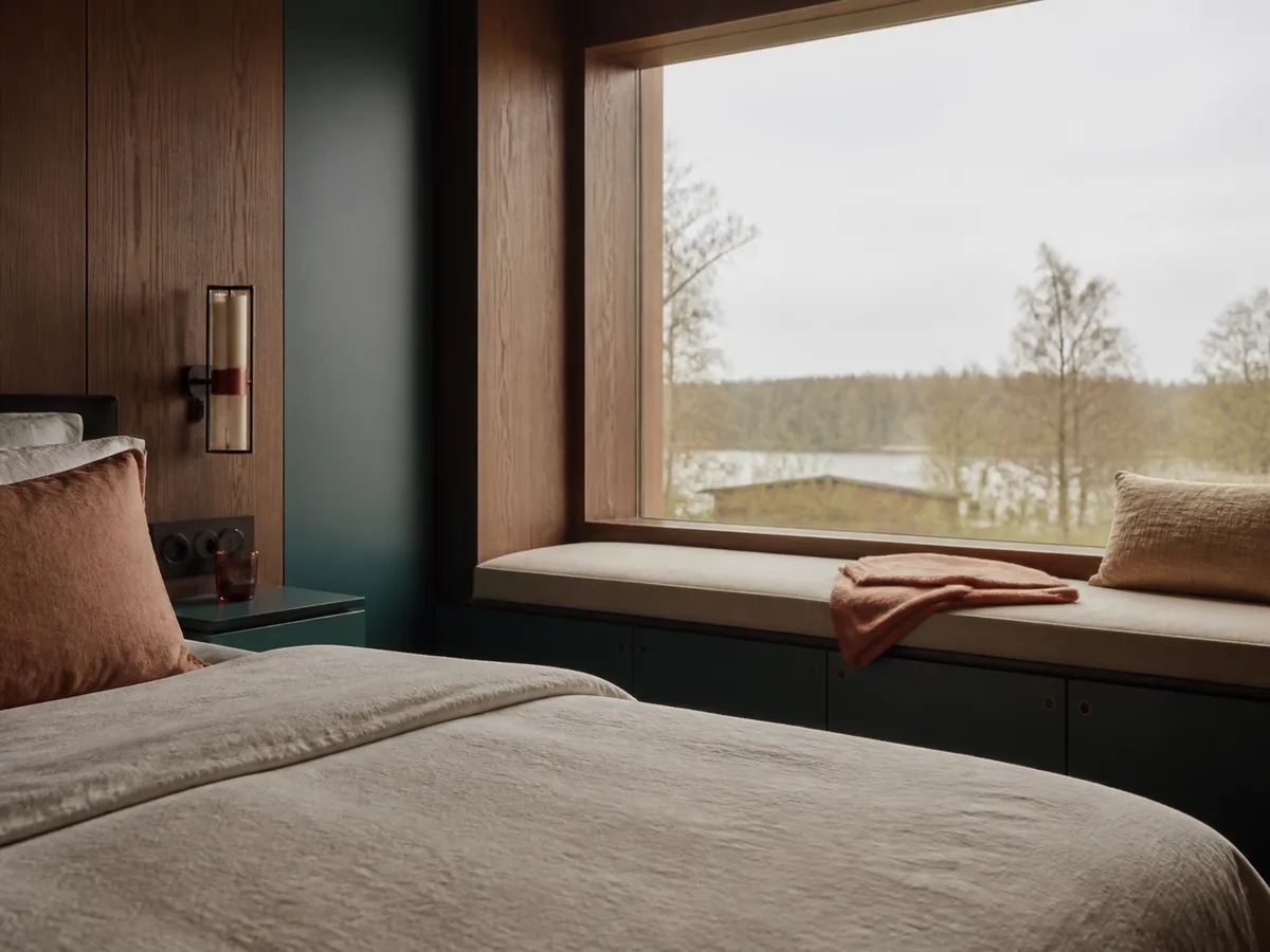 Raamzitbank en beddetail in een rustige kamer